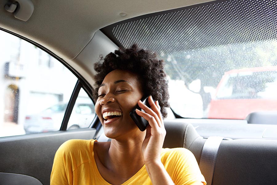 Client Center - Laughing Young Woman in a Car Talking on Her Mobile Phone
